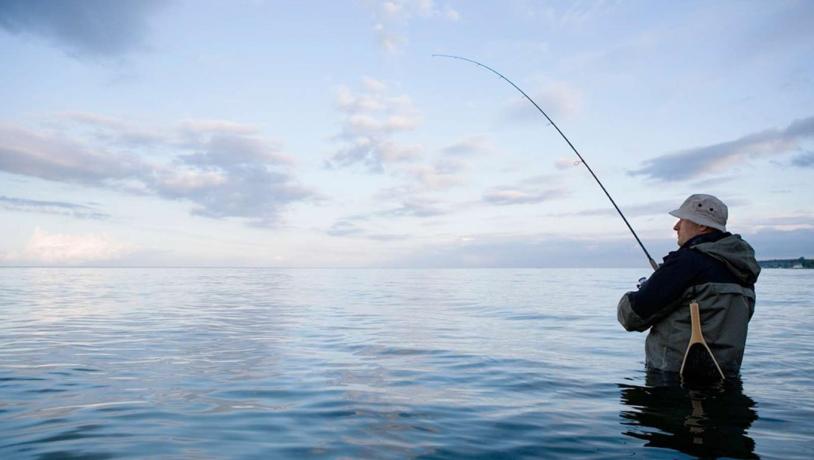 Man fishing in the sea at sunset