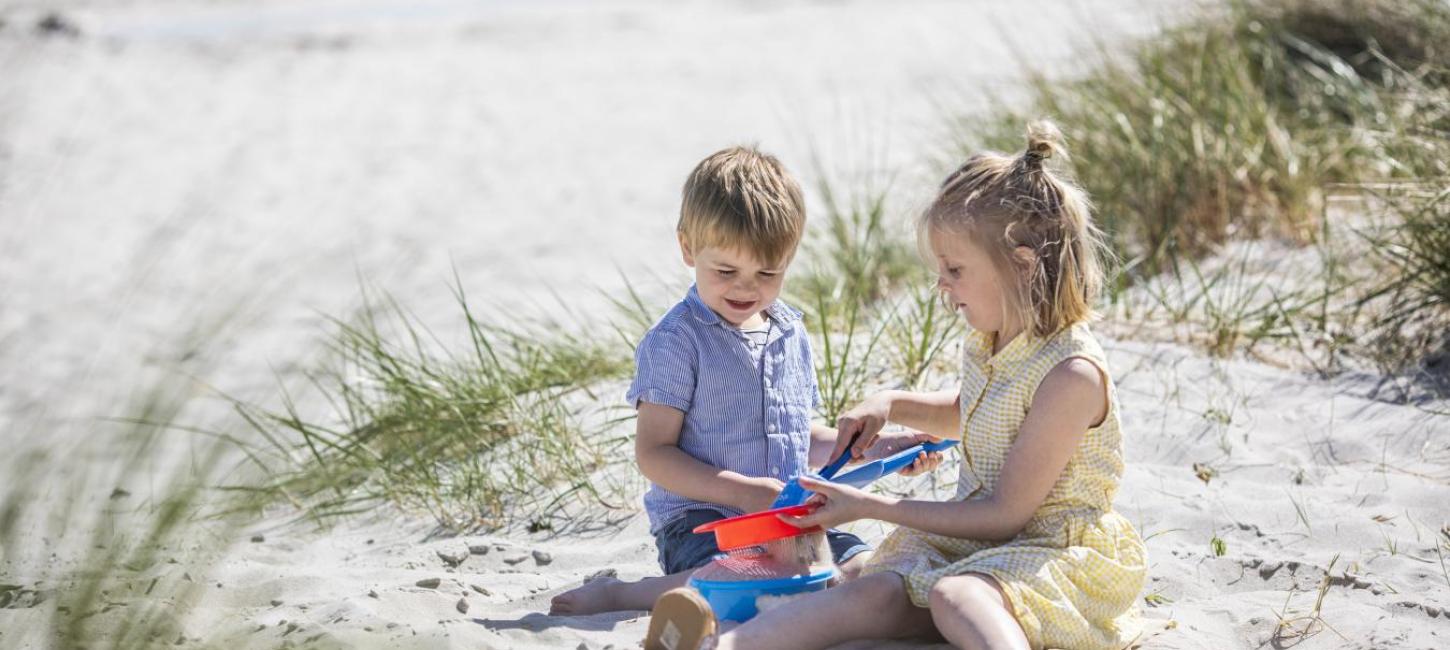 Children playing on the white sandy beach in Saksild