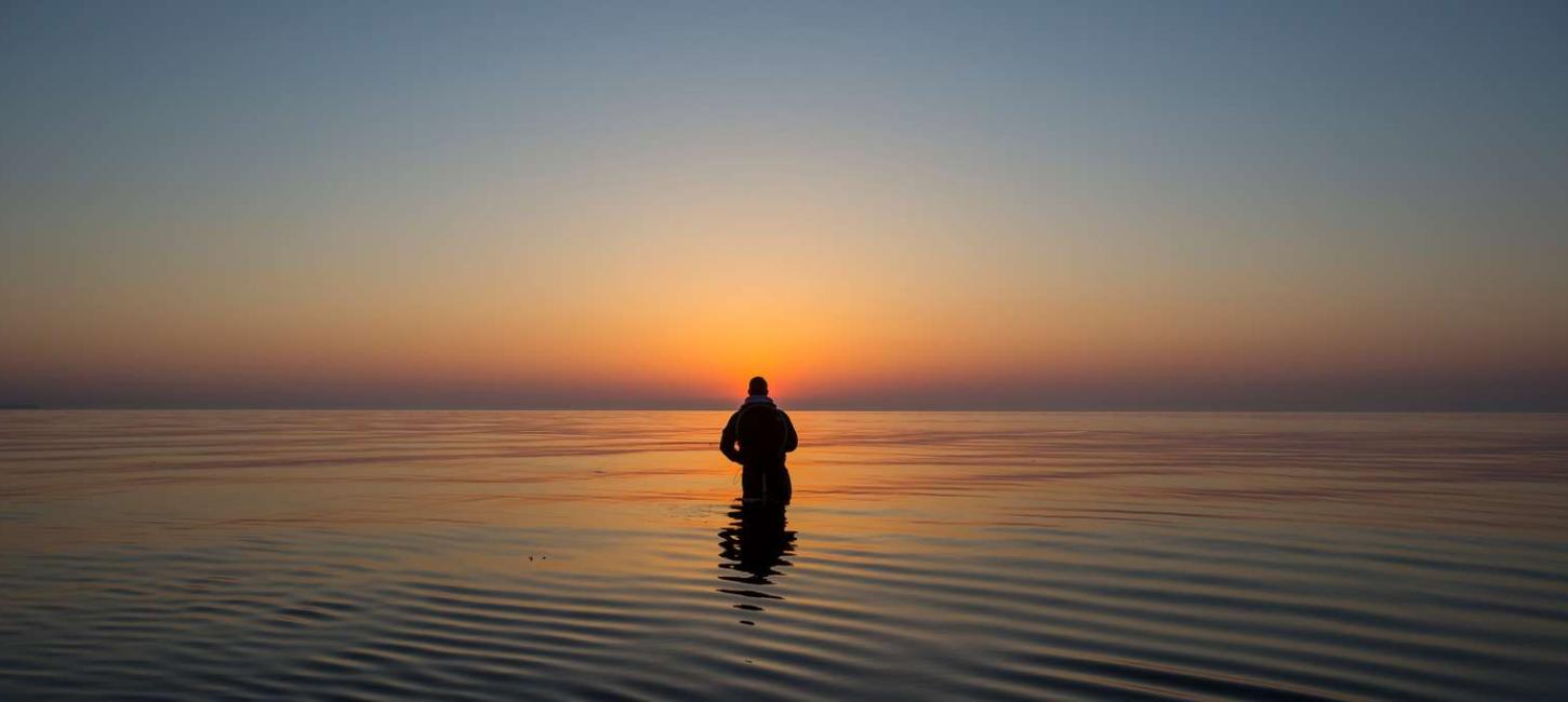 Man fishing in the sea at sunrise